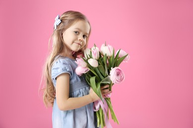 Cute little girl with bouquet of beautiful spring flowers on pink background