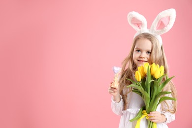 Photo of Cute little girl with bunny ears and tulips on pink background, space for text. Easter celebration