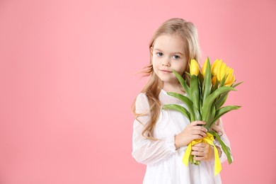 Cute little girl with beautiful yellow tulips on pink background, space for text. Spring season