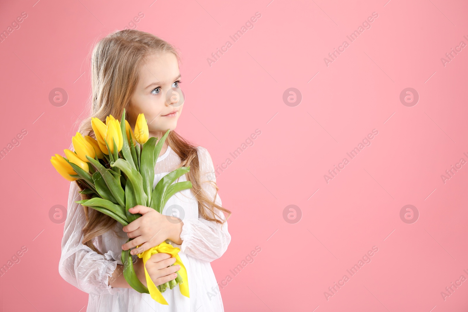 Photo of Cute little girl with beautiful yellow tulips on pink background, space for text. Spring season