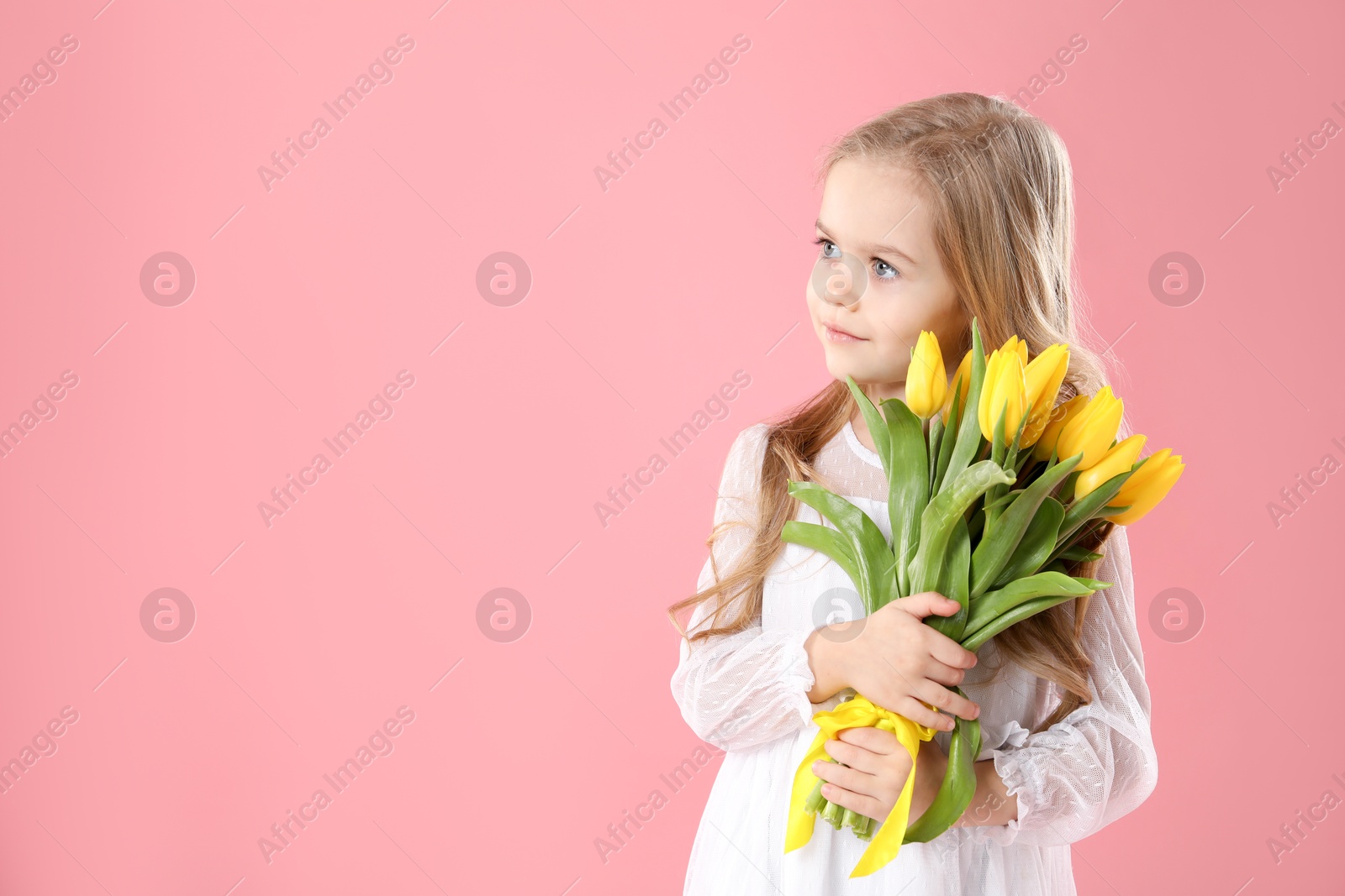 Photo of Cute little girl with beautiful yellow tulips on pink background, space for text. Spring season