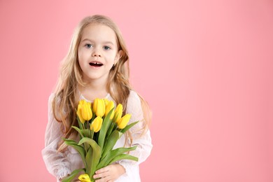 Photo of Cute little girl with beautiful yellow tulips on pink background, space for text. Spring season