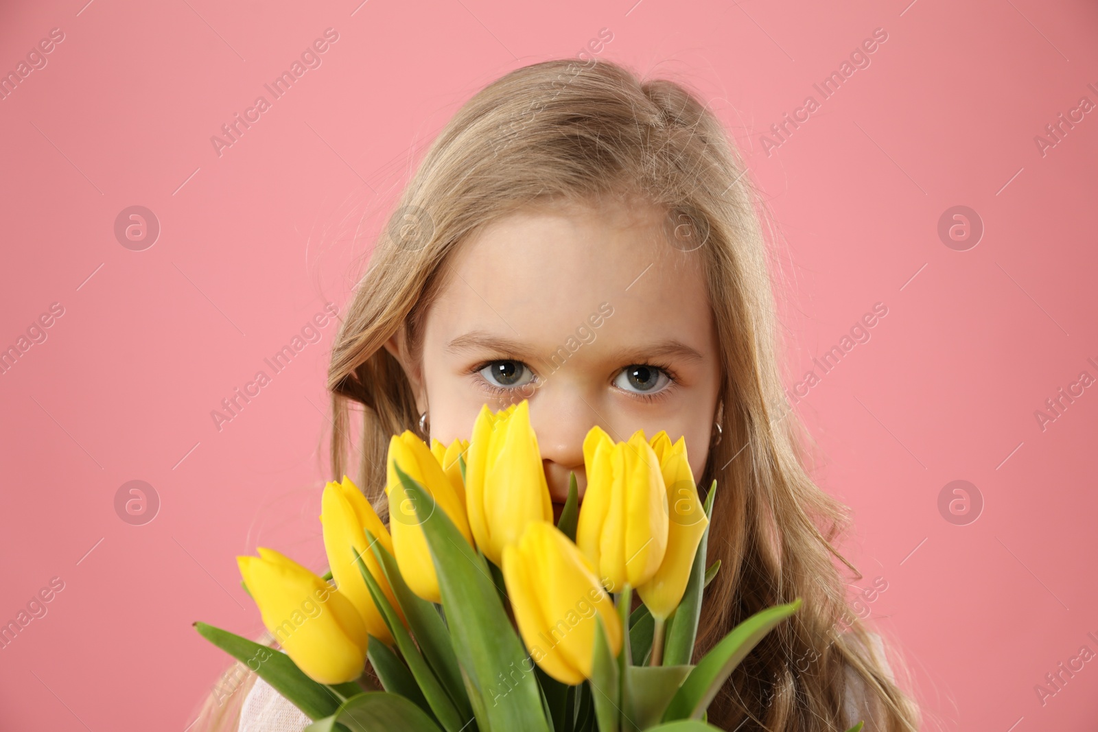 Photo of Cute little girl with beautiful yellow tulips on pink background. Spring season