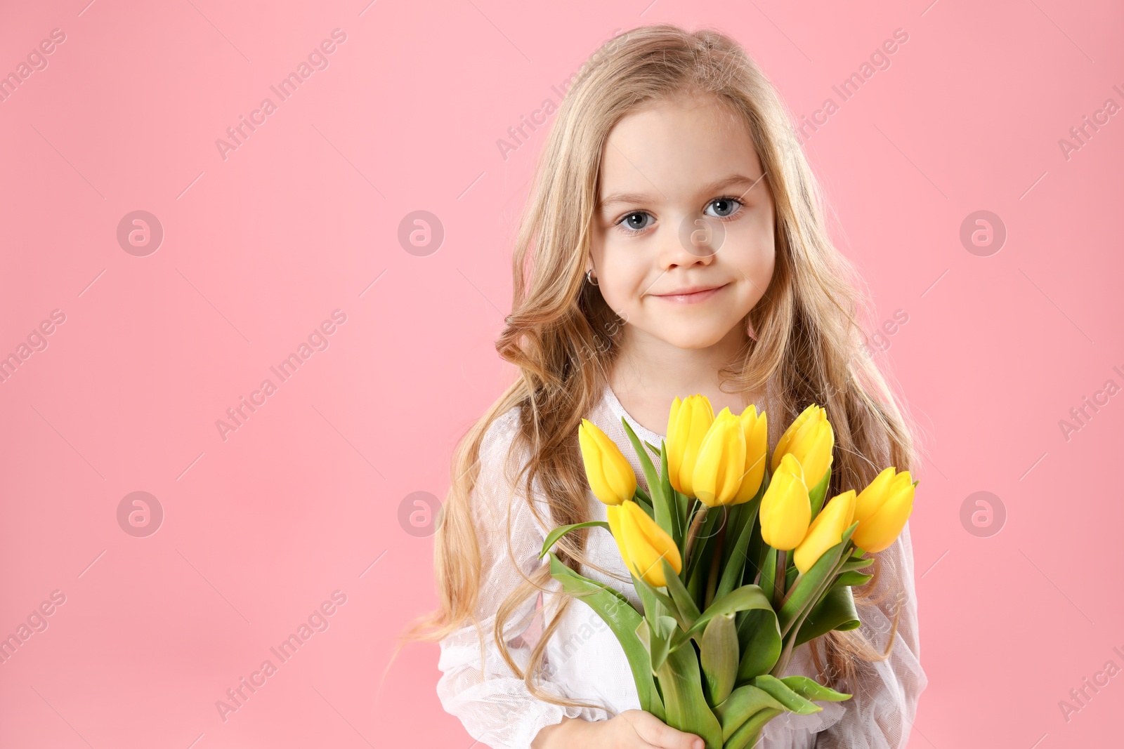 Photo of Cute little girl with beautiful yellow tulips on pink background, space for text. Spring season