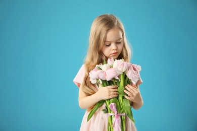 Photo of Cute little girl with bouquet of beautiful spring flowers on light blue background