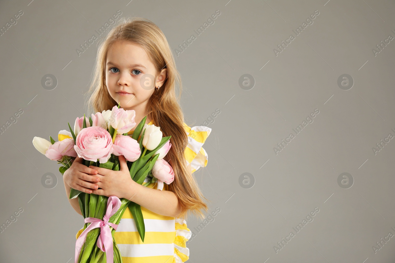 Photo of Cute little girl with bouquet of beautiful spring flowers on gray background, space for text