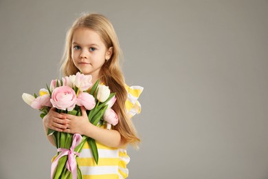 Cute little girl with bouquet of beautiful spring flowers on gray background, space for text