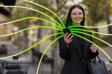 Happy woman using mobile phone outdoors. Bright lines coming out of device symbolizing high speed internet