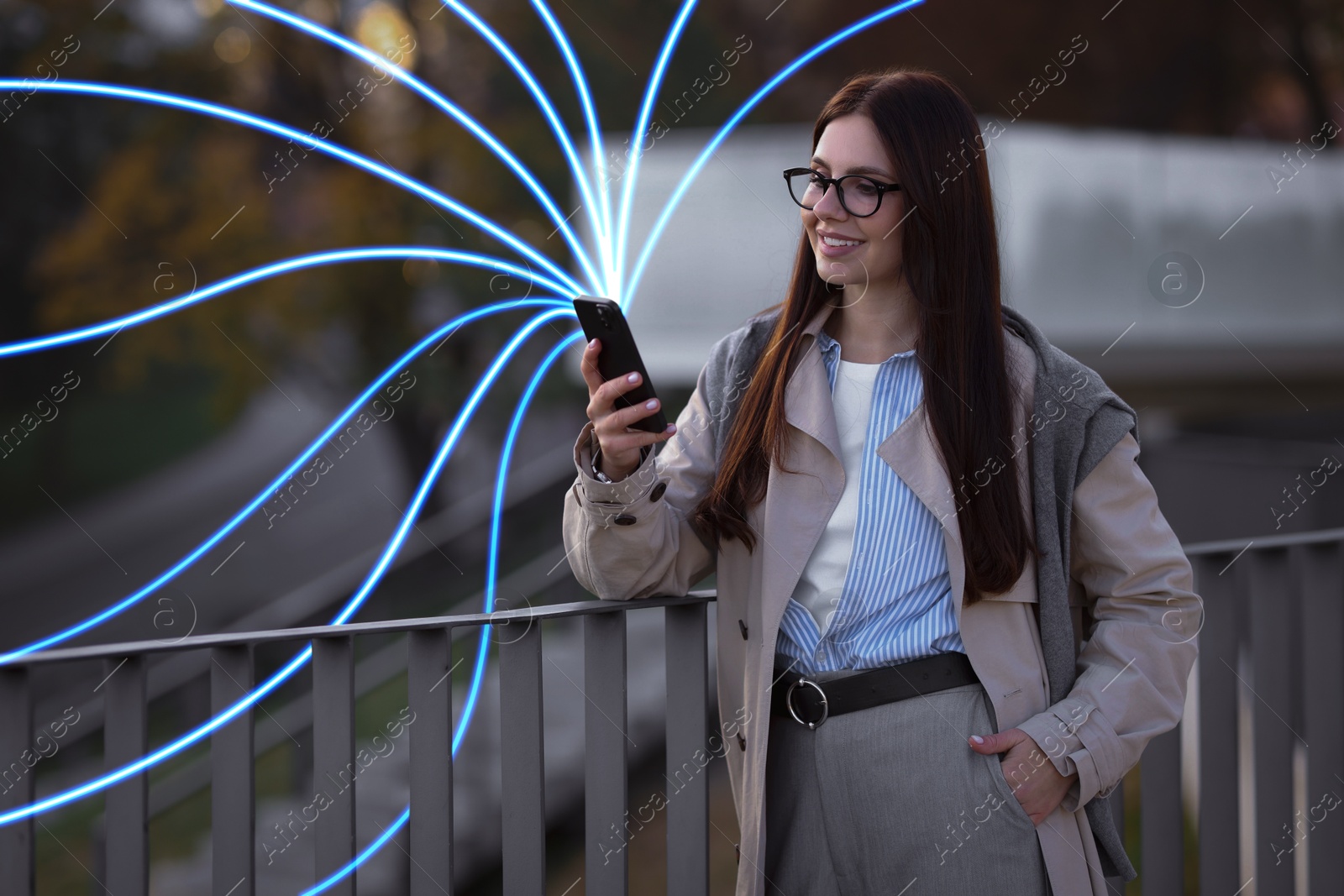 Image of Happy woman using mobile phone outdoors. Bright lines coming out of device symbolizing high speed internet