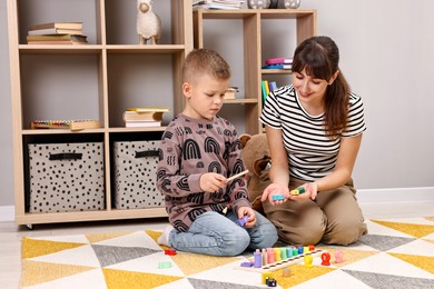 Photo of Autism therapy. Smiling psychologist and little boy playing with educational toy in mental health center