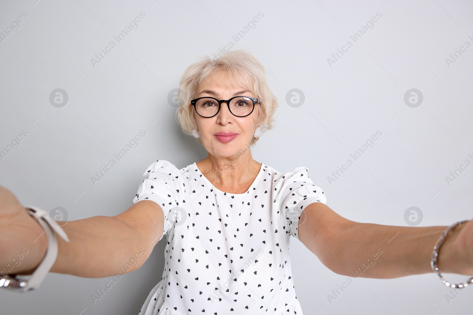 Photo of Elegant grandmother taking selfie on light grey background