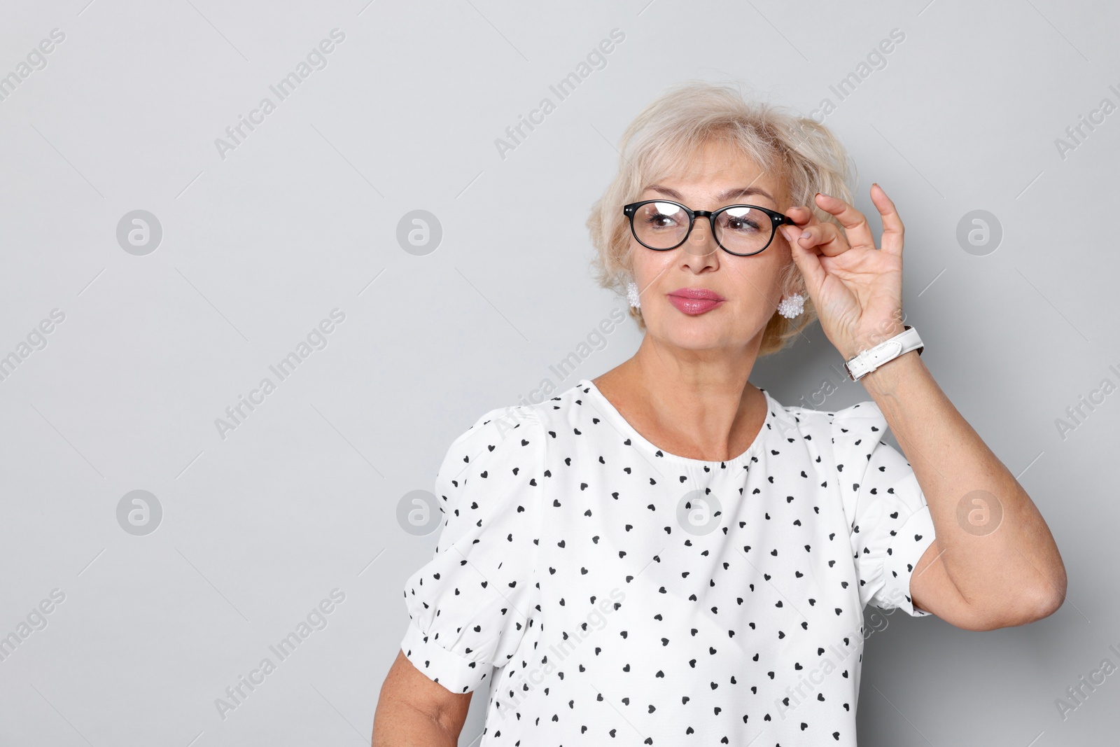 Photo of Portrait of elegant grandmother in glasses on light grey background. Space for text