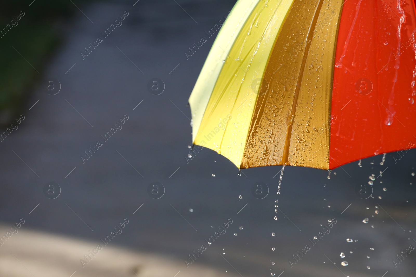 Photo of Open bright umbrella under pouring rain outdoors, closeup. Space for text