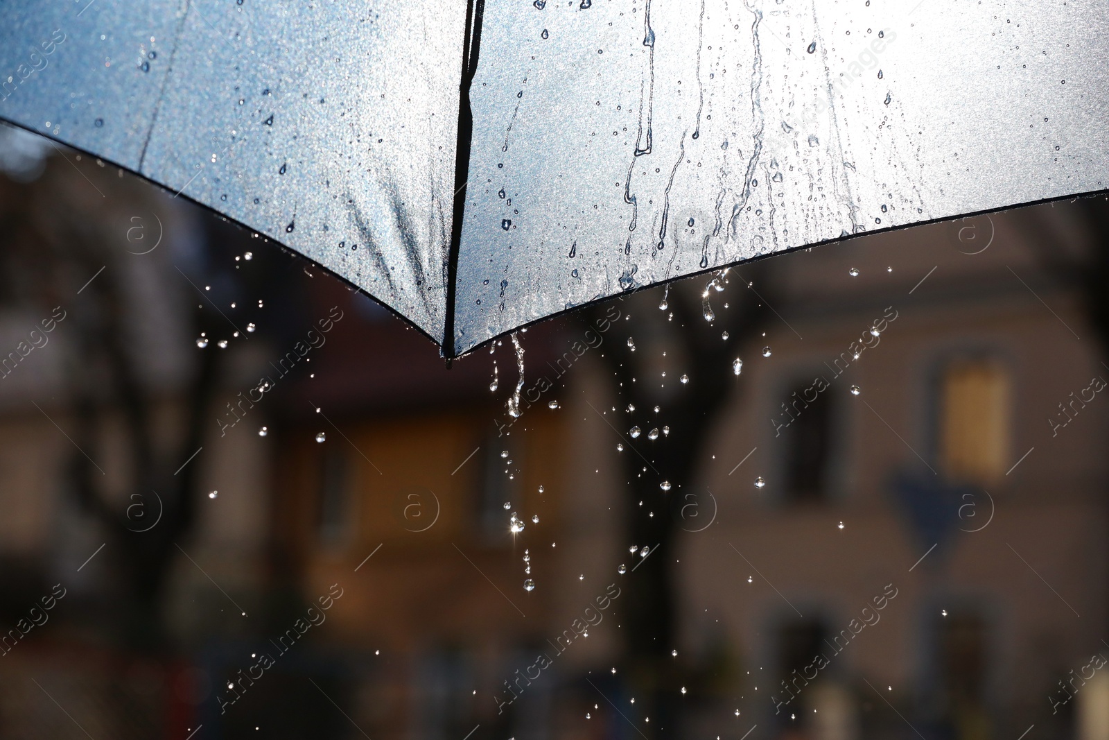 Photo of Open umbrella under pouring rain outdoors, closeup