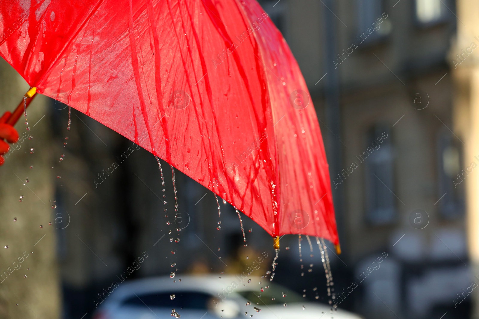 Photo of Open red umbrella under pouring rain outdoors, closeup