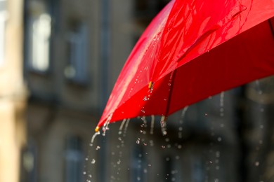 Photo of Open red umbrella under pouring rain outdoors, closeup