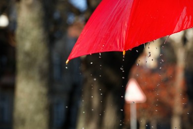 Photo of Open red umbrella under pouring rain outdoors, closeup