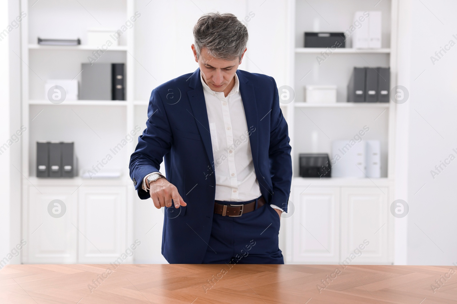 Photo of Man pointing at something on desk in office