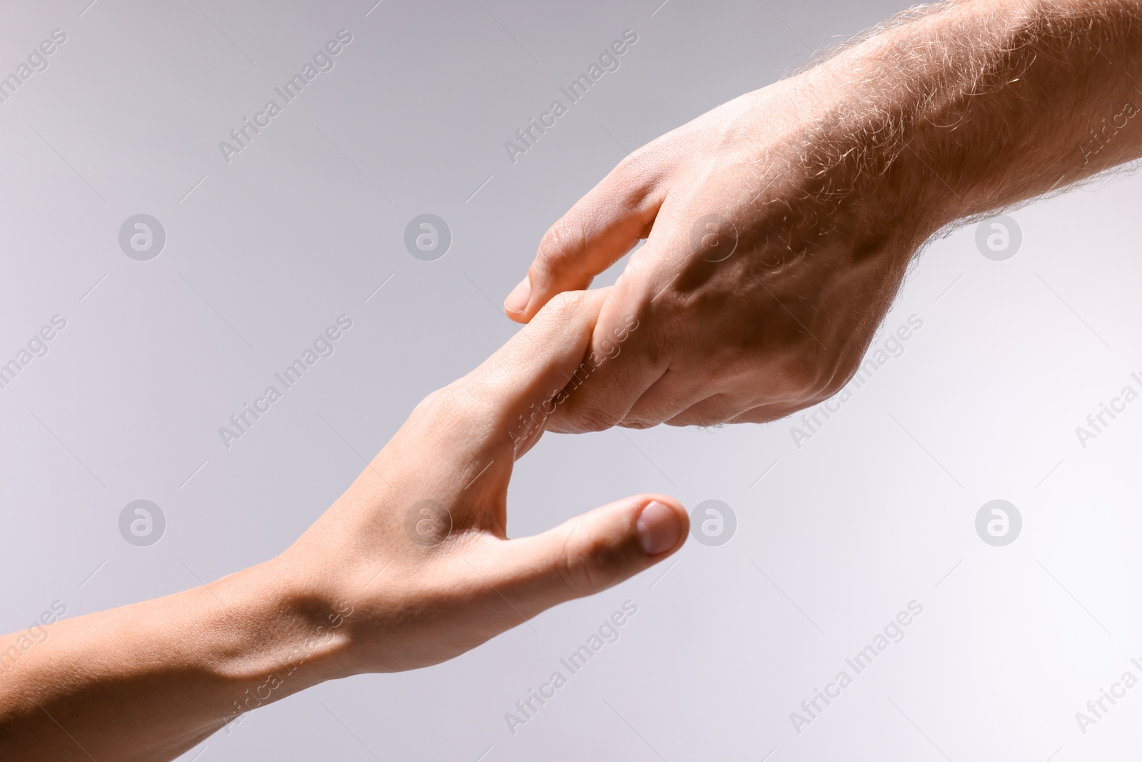 Photo of Help and support. People holding hands on light grey background, closeup