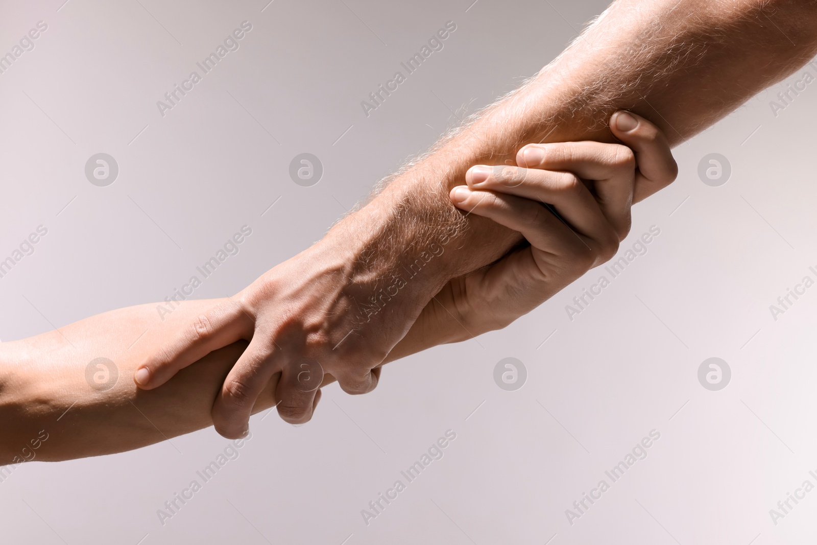 Photo of Help and support. People holding hands on light grey background, closeup