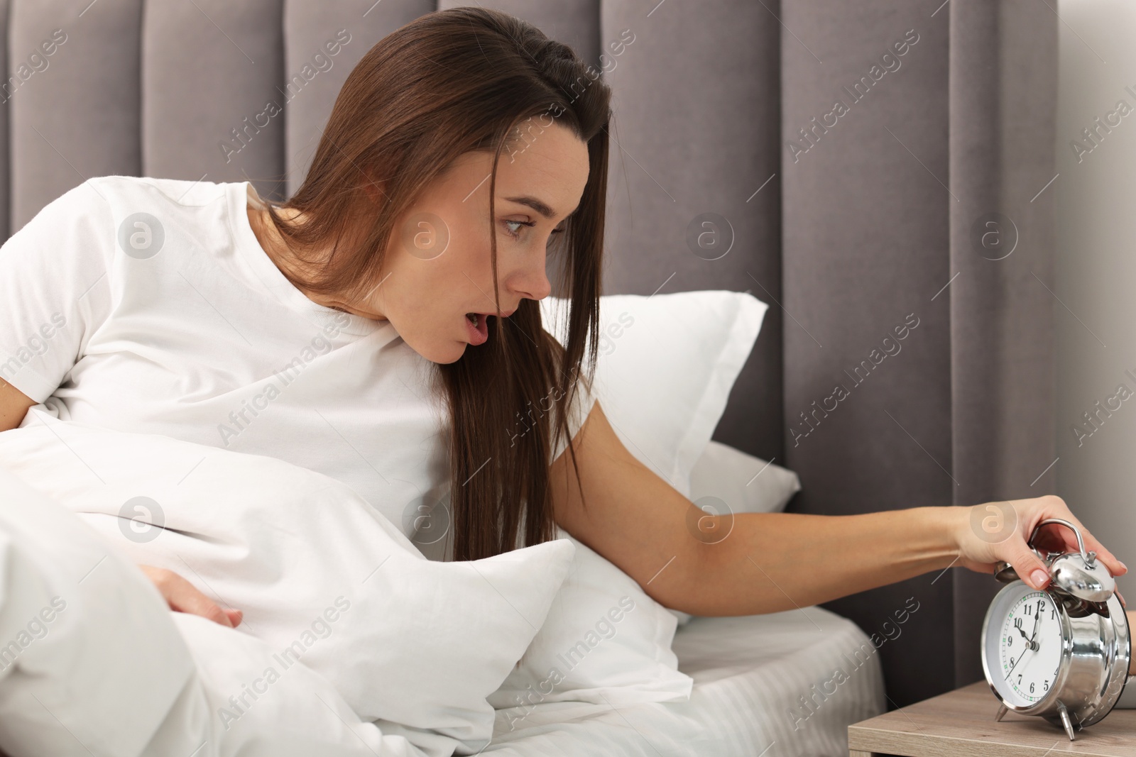 Photo of Overslept woman with alarm clock in bed at home