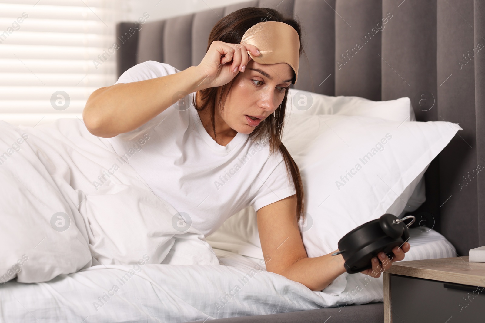 Photo of Overslept woman with alarm clock in bed at home