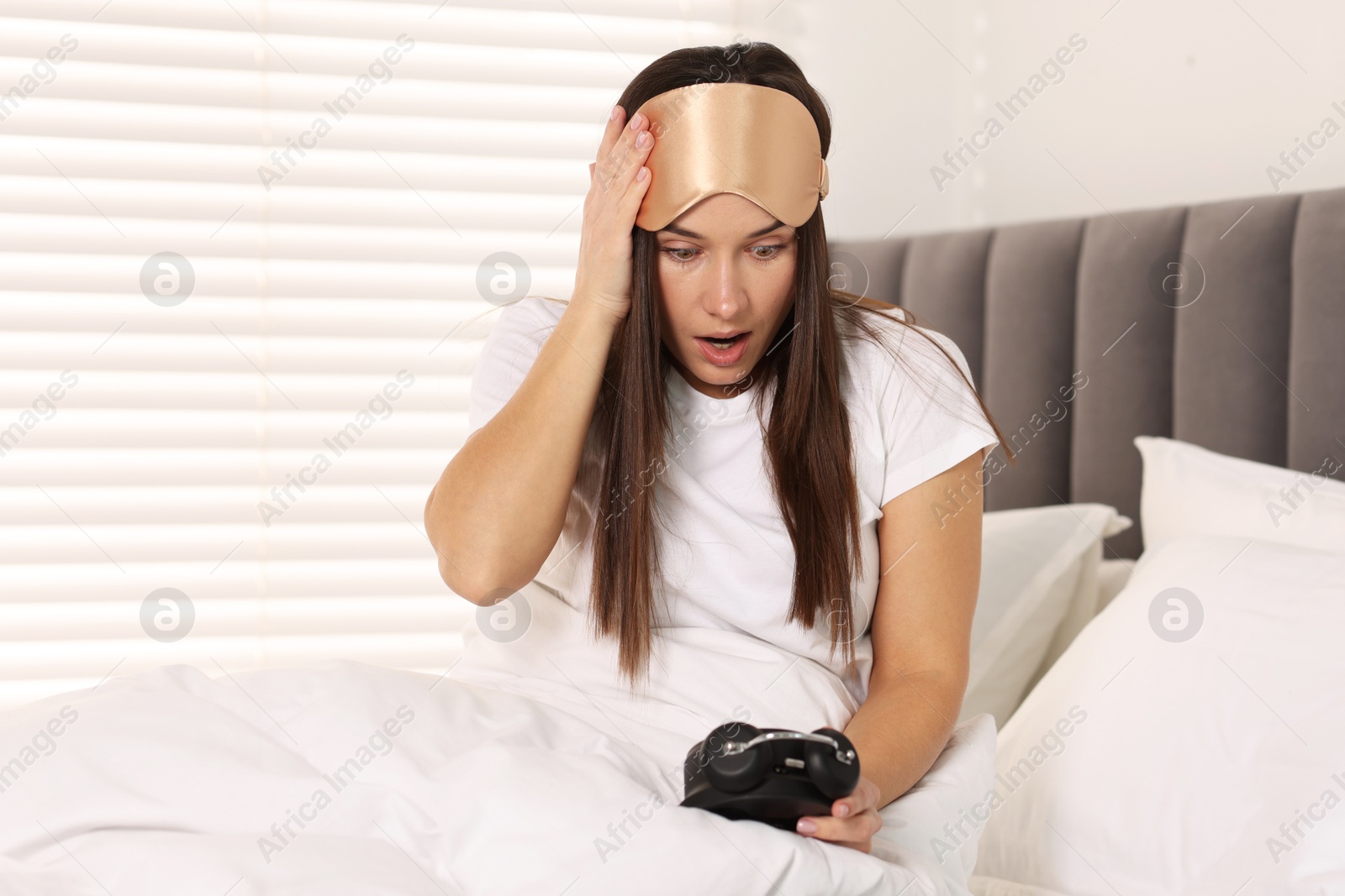 Photo of Overslept woman with alarm clock in bed at home