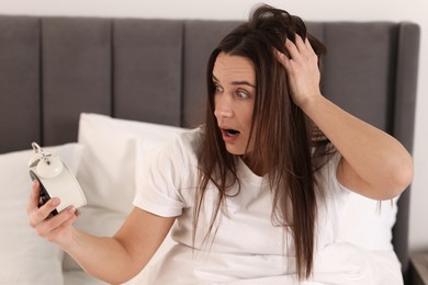 Photo of Overslept woman with alarm clock in bed at home