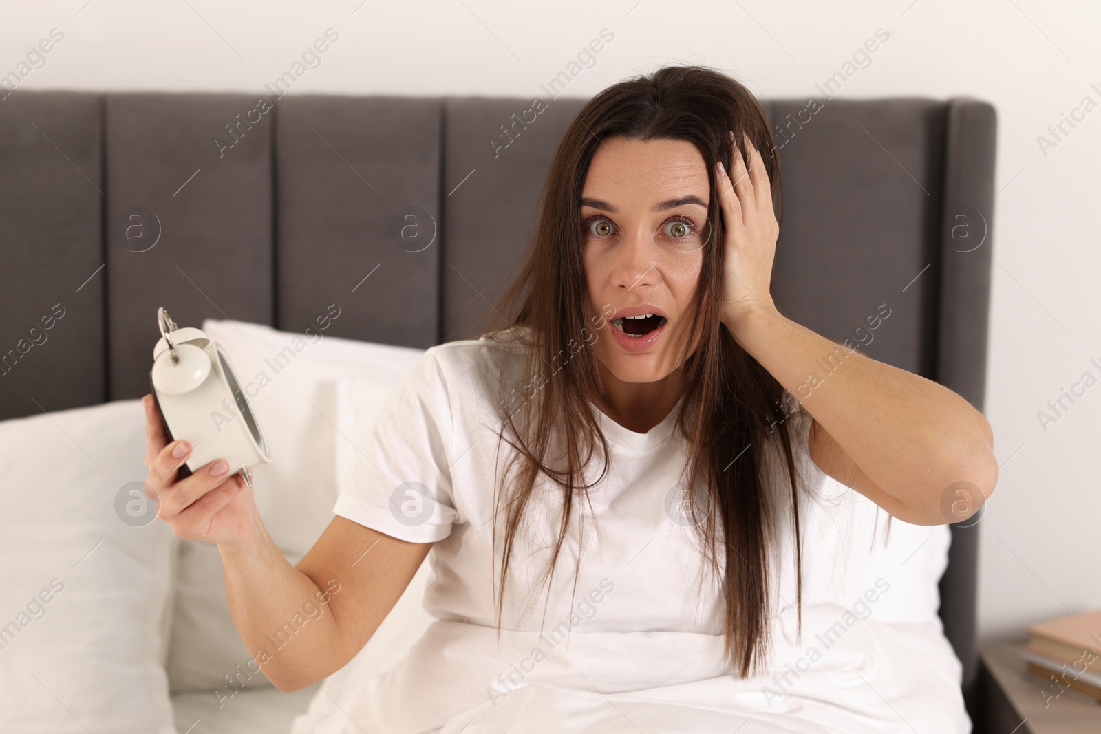 Photo of Overslept woman with alarm clock in bed at home