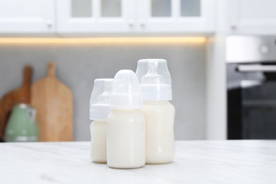 Photo of Feeding bottles with milk on white table indoors