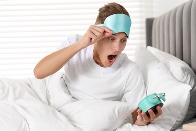 Photo of Overslept man with alarm clock in bed at home