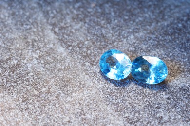 Photo of Beautiful shiny light blue gemstones on stone, space for text