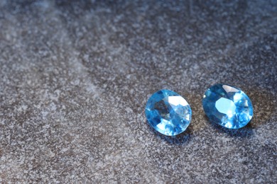 Photo of Beautiful shiny light blue gemstones on stone, space for text