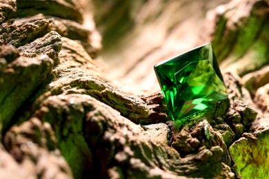 Photo of Beautiful shiny green gemstone on stone, closeup