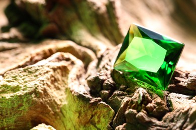 Photo of Beautiful shiny green gemstone on stone, closeup