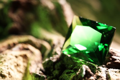 Photo of Beautiful shiny green gemstone on stone, closeup. Space for text