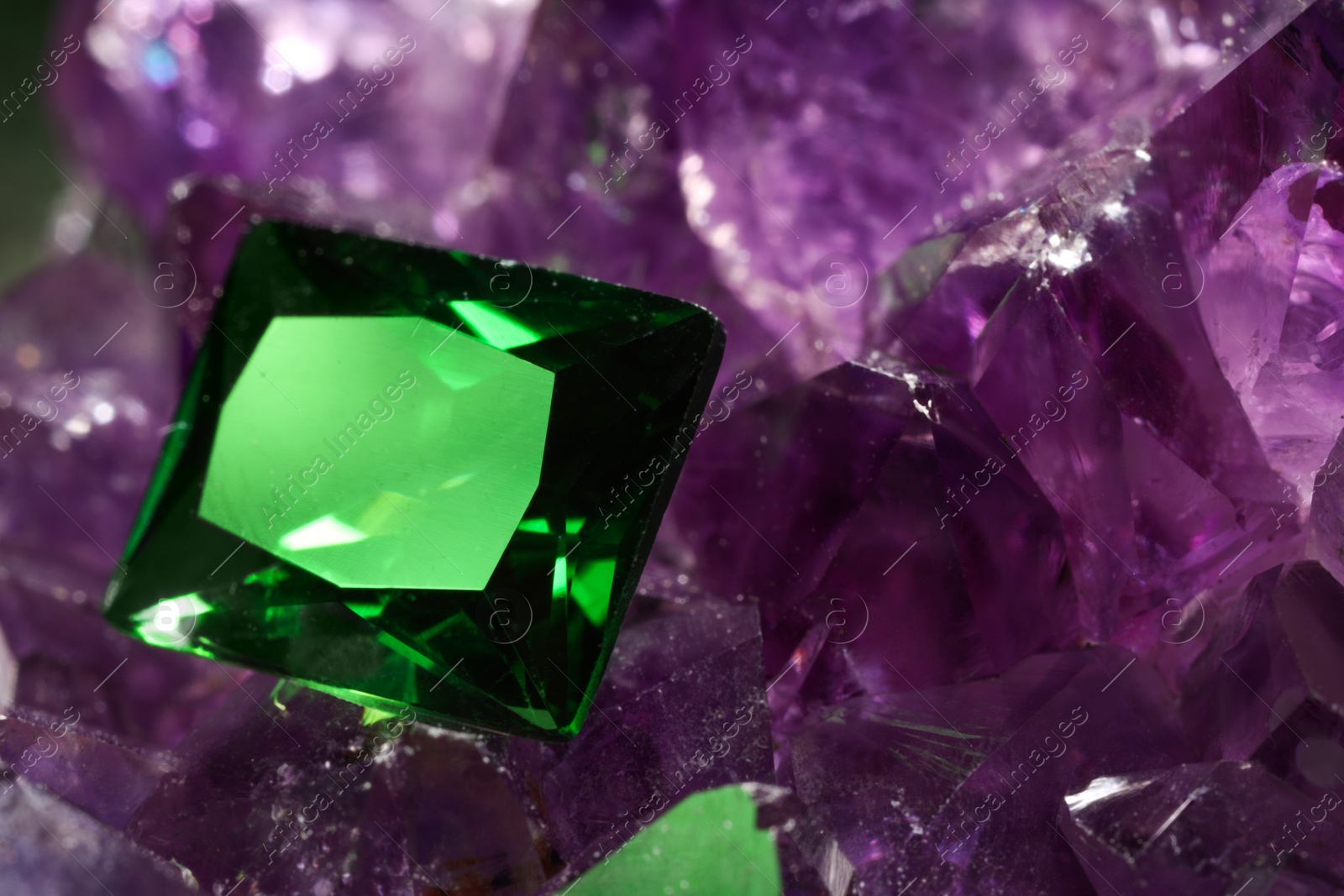 Photo of Beautiful shiny green gemstone on natural amethyst, closeup