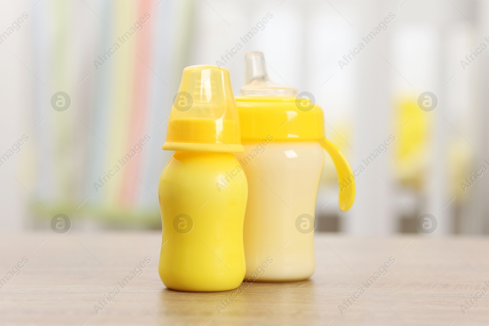 Photo of Feeding bottles with milk on wooden table indoors