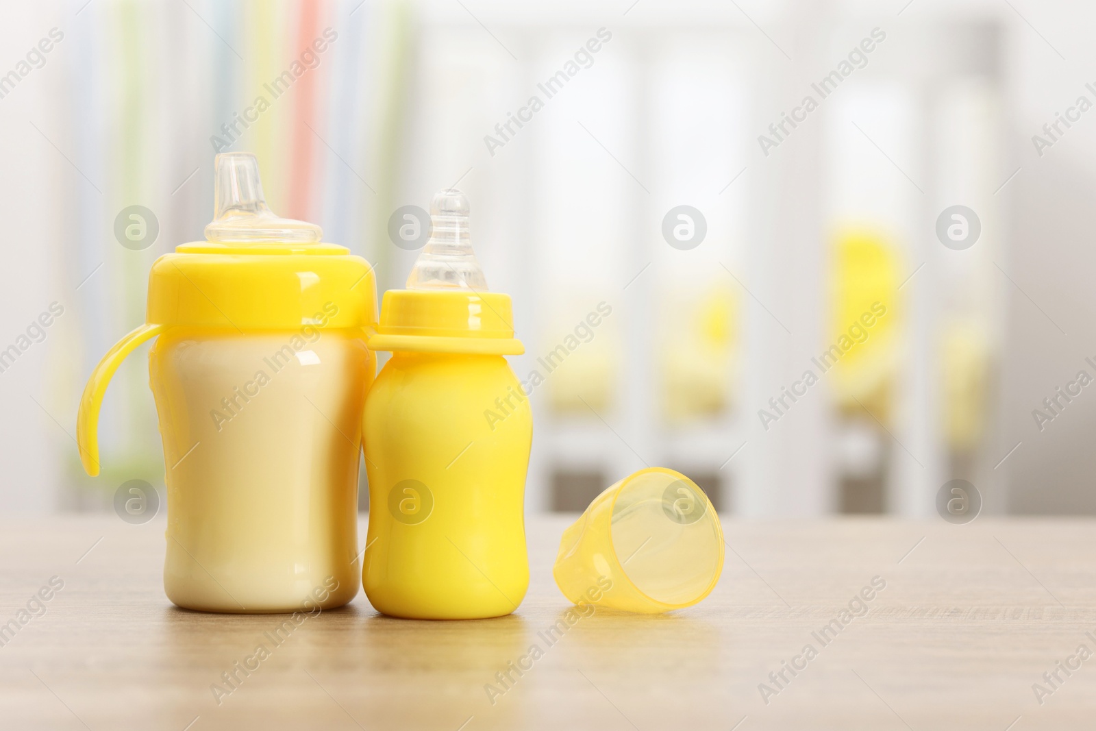 Photo of Feeding bottles with milk on wooden table indoors