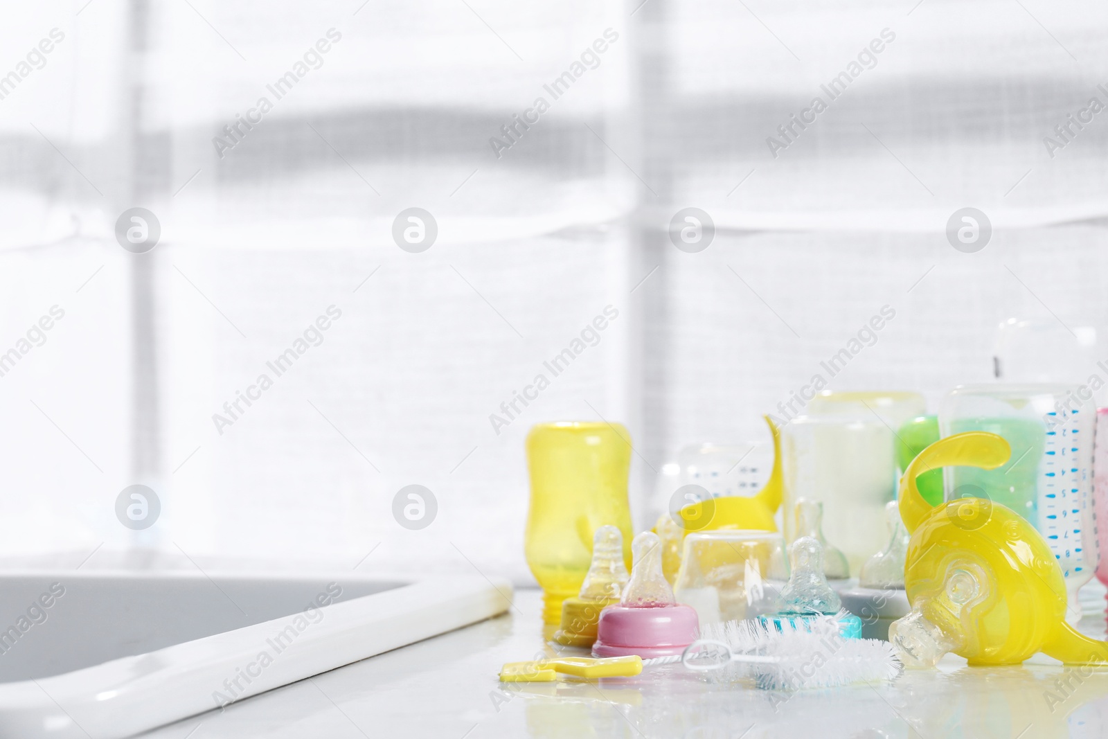 Photo of Clean feeding bottles drying on counter indoors. Space for text