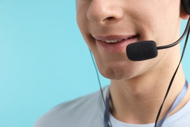 Photo of Technical support call center. Smiling operator on light blue background, closeup. Space for text