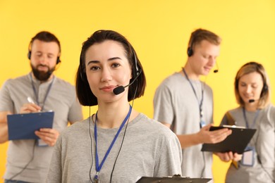 Photo of Technical support call center. Team of friendly operators on yellow background