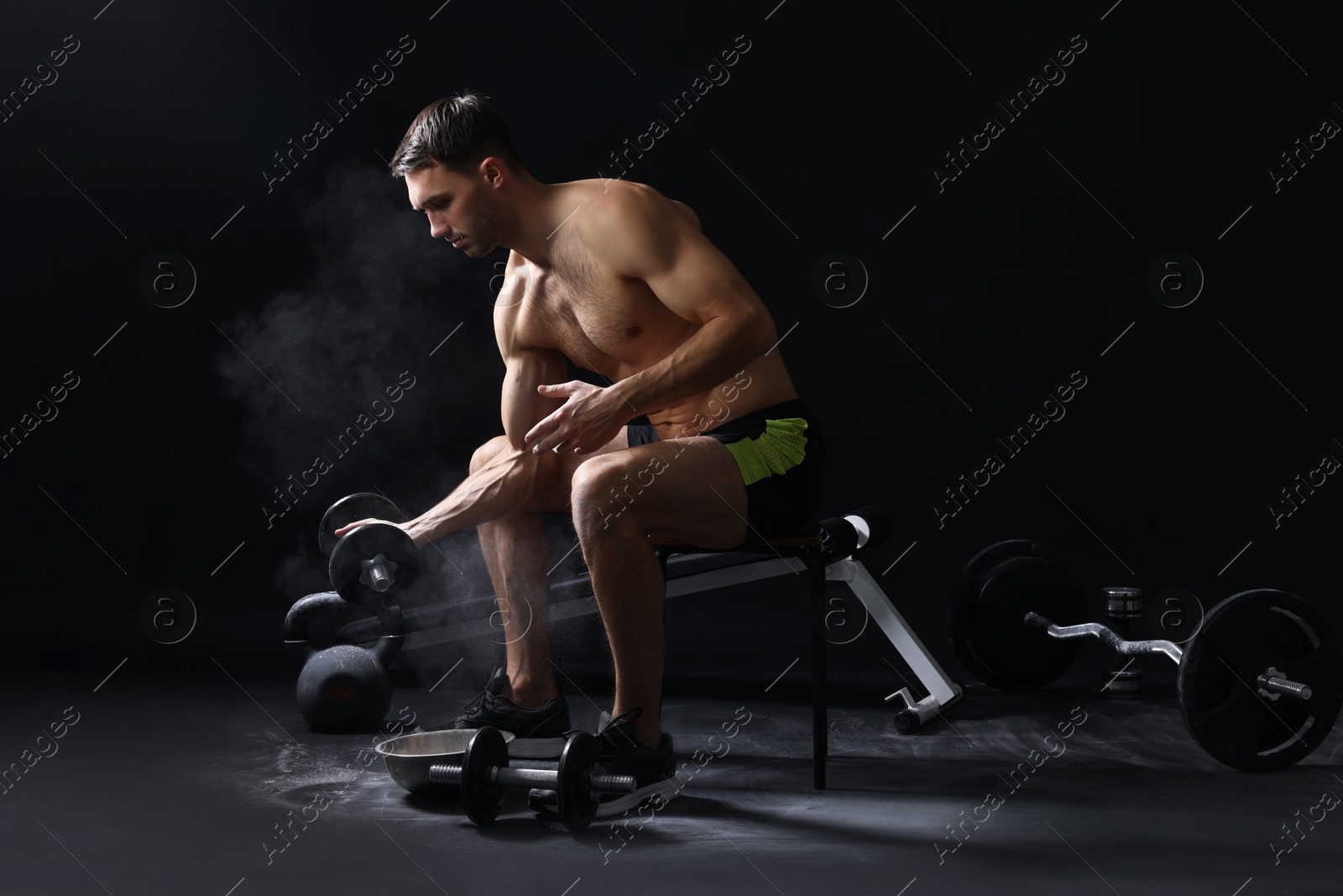 Photo of Man training with barbell against black background