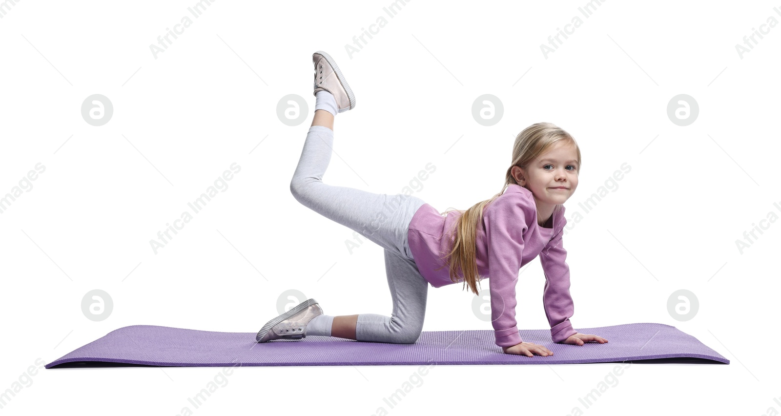 Photo of Little girl exercising on fitness mat against white background. Sport activity