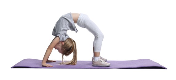 Photo of Little girl exercising on fitness mat against white background. Sport activity