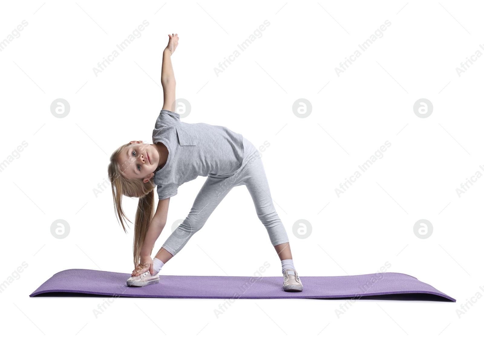 Photo of Little girl exercising on fitness mat against white background. Sport activity