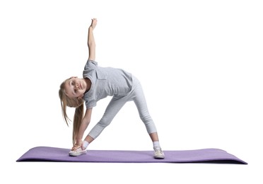 Photo of Little girl exercising on fitness mat against white background. Sport activity