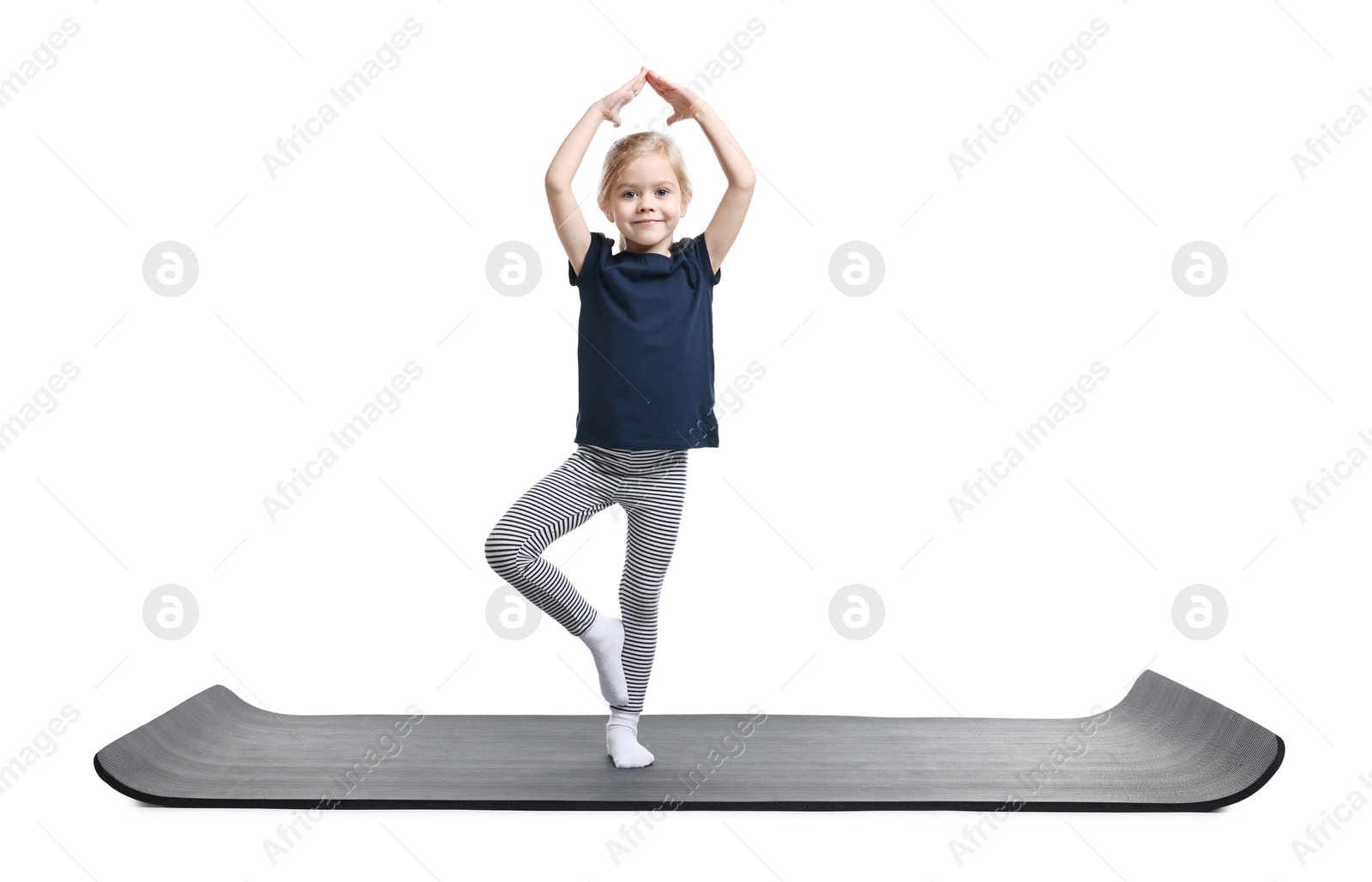 Photo of Little girl exercising on fitness mat against white background. Sport activity