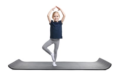 Photo of Little girl exercising on fitness mat against white background. Sport activity