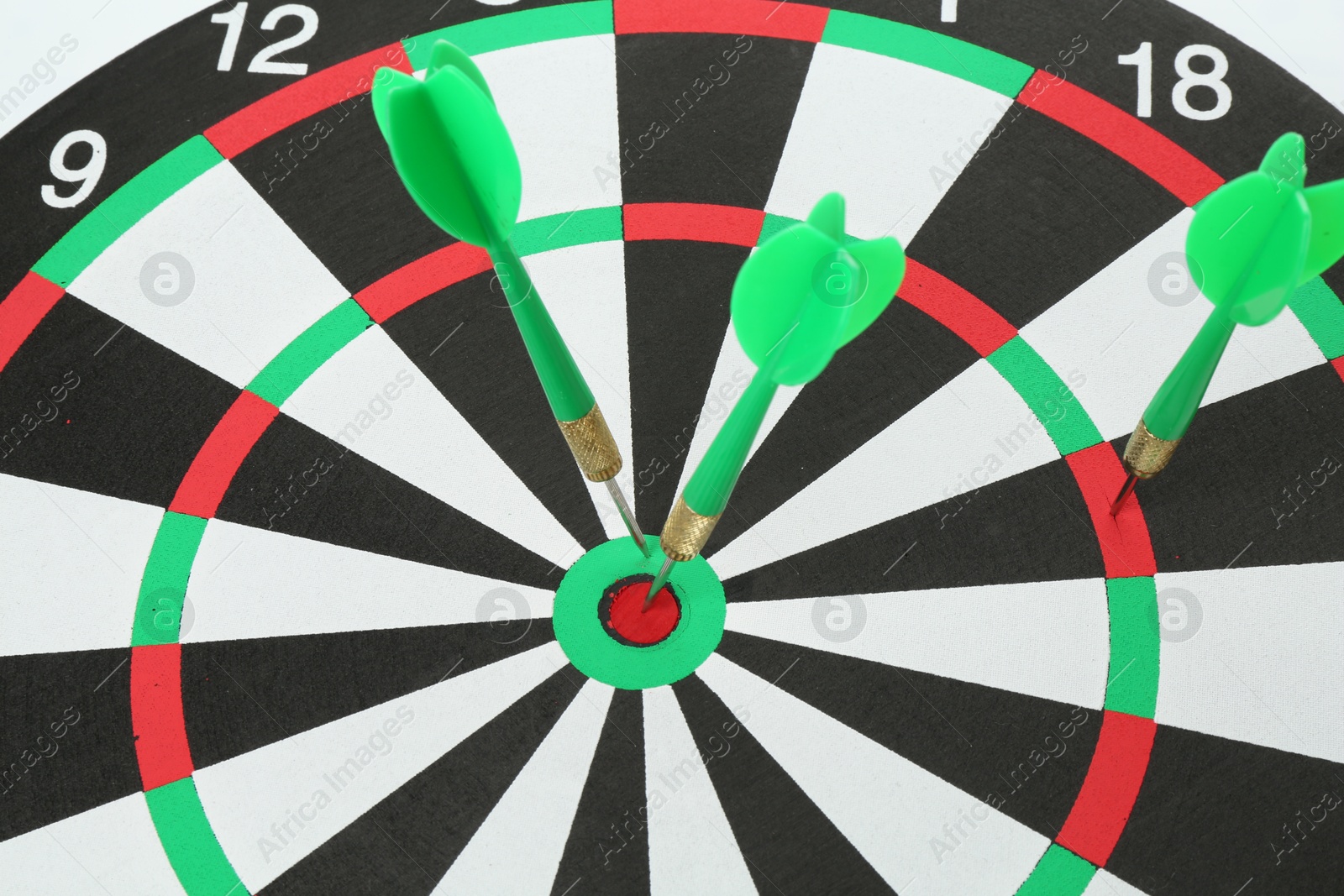 Photo of Dart board with green arrows on white background, closeup